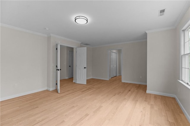 spare room featuring light wood-type flooring, baseboards, ornamental molding, and visible vents
