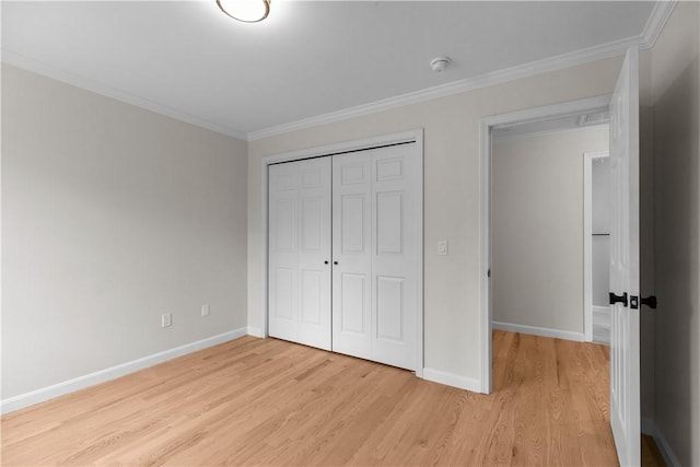 unfurnished bedroom featuring ornamental molding, light wood finished floors, and a closet