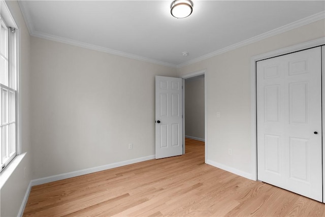 unfurnished bedroom with a closet, light wood-style flooring, baseboards, and ornamental molding