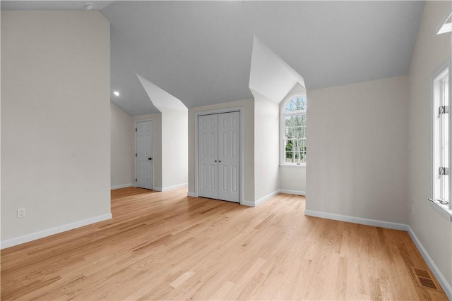 additional living space with light wood finished floors, baseboards, and vaulted ceiling