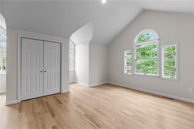unfurnished bedroom with visible vents, baseboards, a closet, light wood-style floors, and vaulted ceiling
