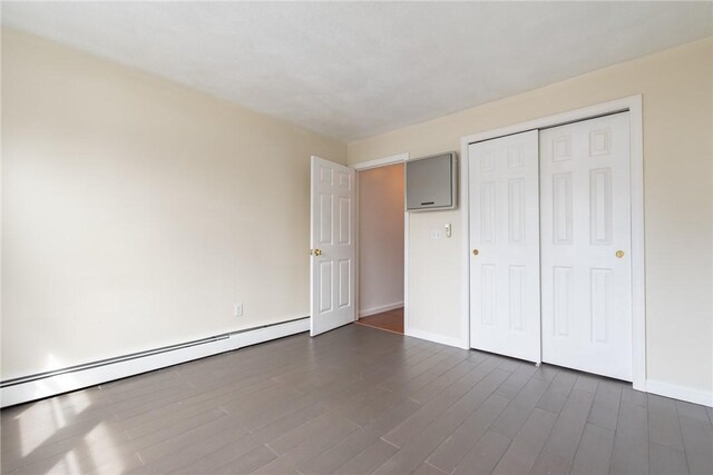 83 Wyndham Ave, Providence, RI 02908 - unfurnished bedroom with a closet, dark wood-type flooring, a baseboard radiator, and baseboards