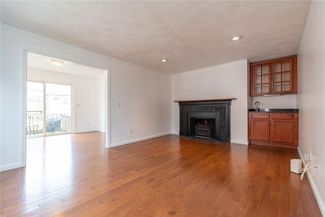 83 Wyndham Ave, Providence, RI 02908 - unfurnished living room featuring a fireplace with flush hearth, wood finished floors, a sink, and baseboards