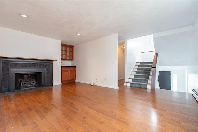 83 Wyndham Ave, Providence, RI 02908 - unfurnished living room featuring baseboards, recessed lighting, stairway, a fireplace with flush hearth, and wood finished floors