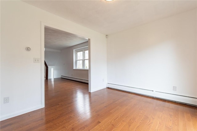 83 Wyndham Ave, Providence, RI 02908 - empty room with a baseboard heating unit, baseboards, stairway, a baseboard radiator, and wood finished floors