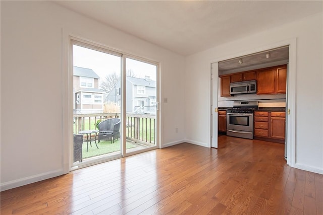 83 Wyndham Ave, Providence, RI 02908 - kitchen featuring stainless steel appliances, baseboards, brown cabinetry, and wood finished floors