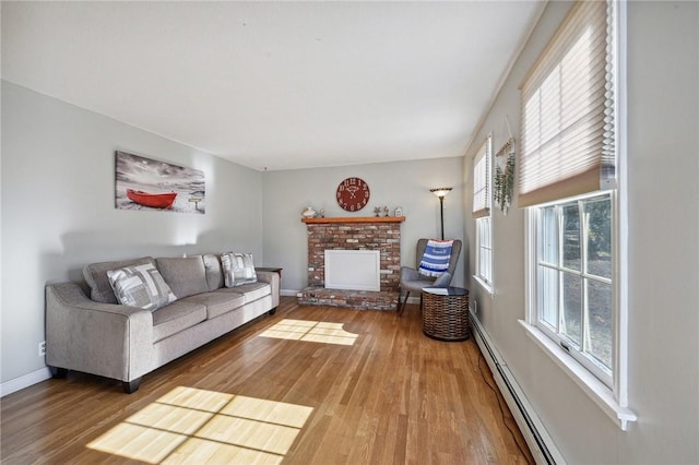 living area featuring a baseboard radiator, wood finished floors, a fireplace, and baseboards