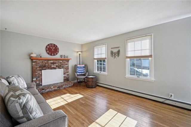 living area featuring a brick fireplace, baseboard heating, and wood finished floors