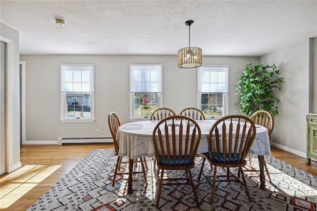 dining space with a chandelier, a baseboard heating unit, a textured ceiling, and wood finished floors
