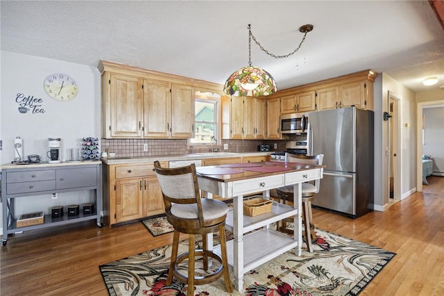 kitchen with tasteful backsplash, light countertops, wood finished floors, and stainless steel appliances