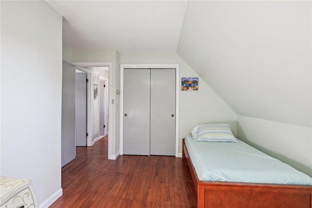bedroom featuring a closet, dark wood-style flooring, baseboards, and lofted ceiling
