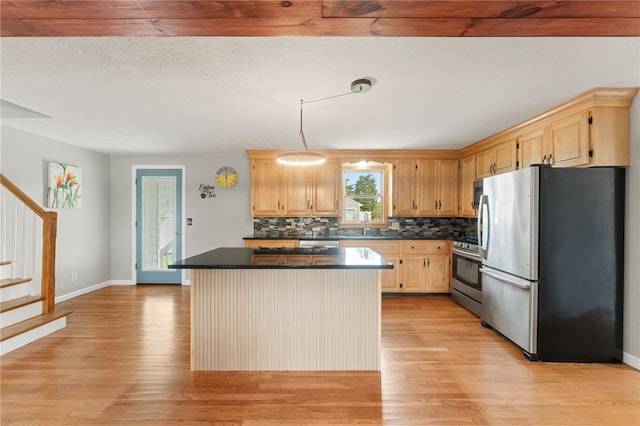 133 Old Pine Rd, Narragansett, RI 02882 - kitchen featuring appliances with stainless steel finishes, dark countertops, light wood finished floors, a center island, and tasteful backsplash