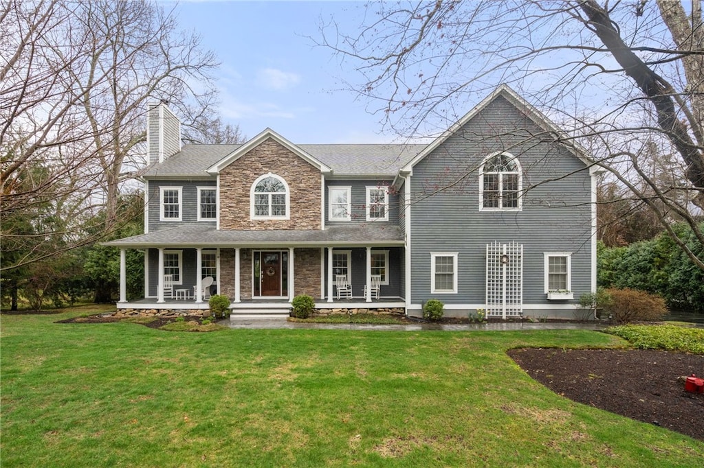 40 Cassandra Ln, North Kingstown, RI 02852 - colonial inspired home featuring a front yard, a porch, stone siding, and a chimney