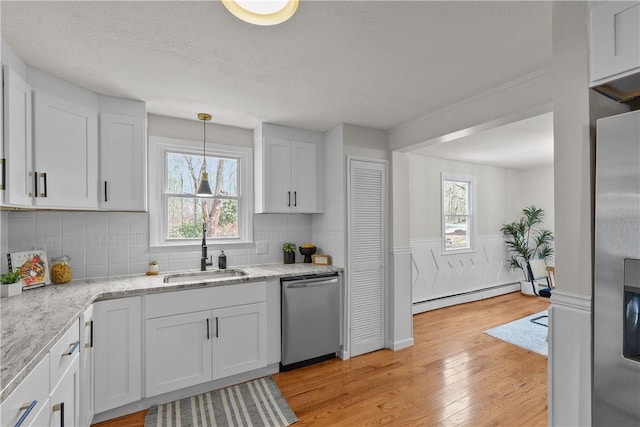 kitchen featuring dishwasher, a sink, light wood-style floors, a healthy amount of sunlight, and baseboard heating