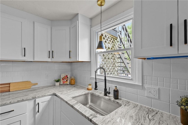 kitchen with tasteful backsplash, a sink, and white cabinetry