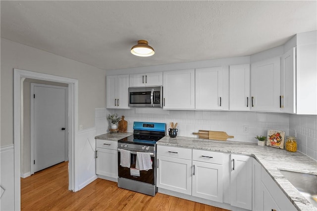 kitchen featuring white cabinetry, light wood-style flooring, appliances with stainless steel finishes, and decorative backsplash
