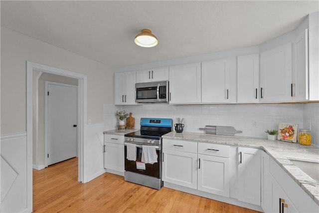 kitchen featuring white cabinetry, tasteful backsplash, appliances with stainless steel finishes, and light wood finished floors