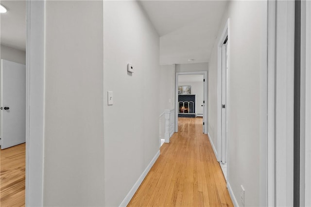corridor with light wood-type flooring and baseboards