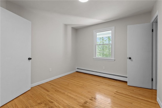 unfurnished bedroom with a baseboard radiator, light wood finished floors, and baseboards