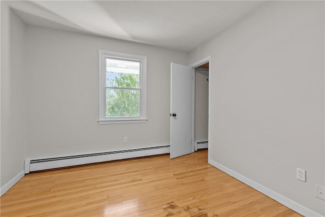 unfurnished room featuring light wood-style floors, baseboard heating, and baseboards