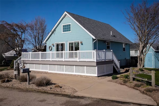 back of house featuring roof with shingles, a wooden deck, and stairway