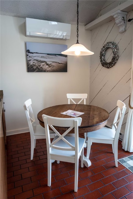 unfurnished dining area with brick floor, baseboards, and a wall unit AC