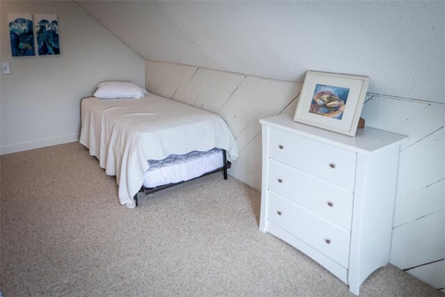 bedroom with light colored carpet and lofted ceiling