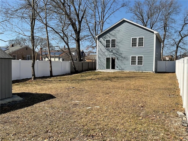 back of property with a lawn and a fenced backyard