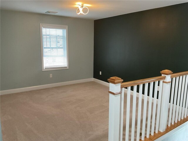 unfurnished room with light carpet, visible vents, and baseboards