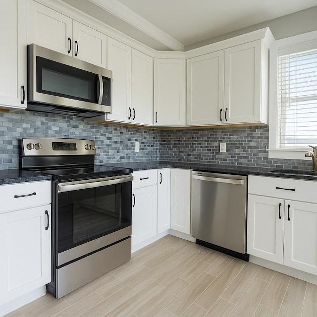 kitchen with white cabinetry, a sink, backsplash, and appliances with stainless steel finishes