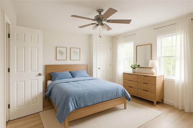 bedroom with baseboards, ceiling fan, and light wood-style floors
