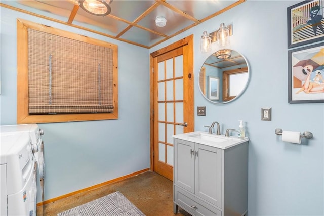 bathroom with concrete flooring, washing machine and clothes dryer, vanity, and baseboards