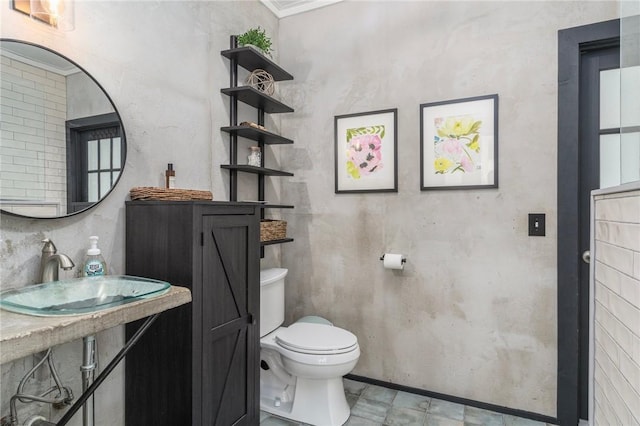half bathroom with toilet, a sink, and baseboards