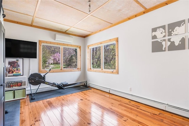 workout area featuring a wealth of natural light, light wood-type flooring, an AC wall unit, and baseboard heating