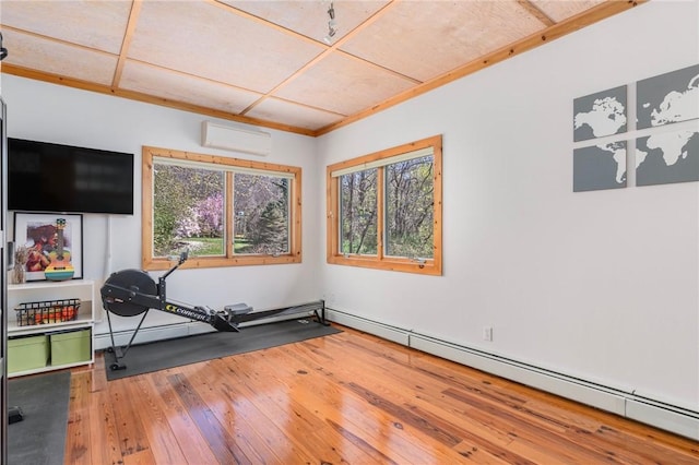 exercise area with a wall mounted AC, hardwood / wood-style floors, and a wealth of natural light