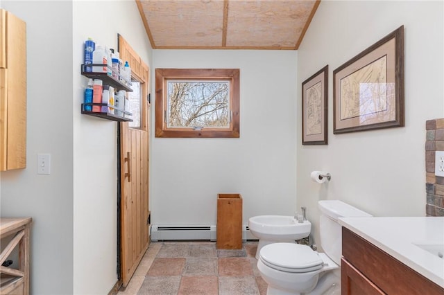 bathroom with stone tile flooring, baseboard heating, toilet, a bidet, and vanity