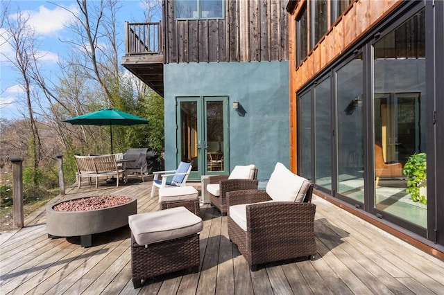 deck with an outdoor living space with a fire pit and french doors