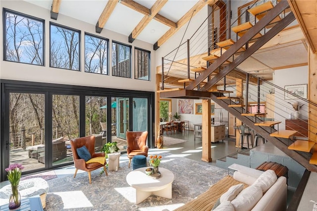 living area with beamed ceiling, a high ceiling, and stairway