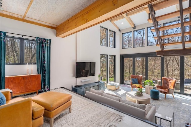 living area featuring high vaulted ceiling, beamed ceiling, and a healthy amount of sunlight