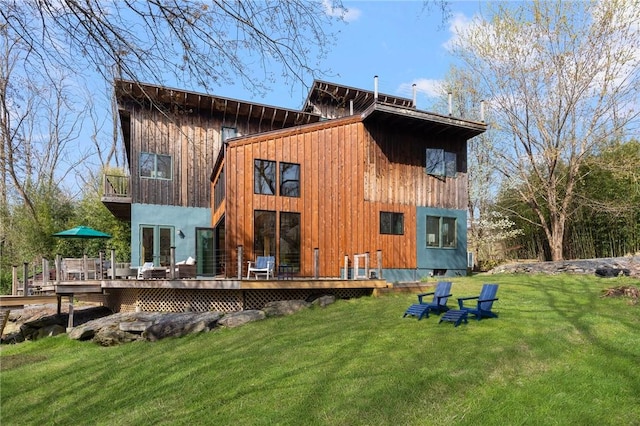 rear view of house featuring a wooden deck, a yard, and a balcony
