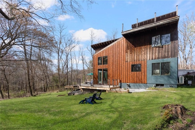 back of property featuring a lawn, board and batten siding, and a wooden deck