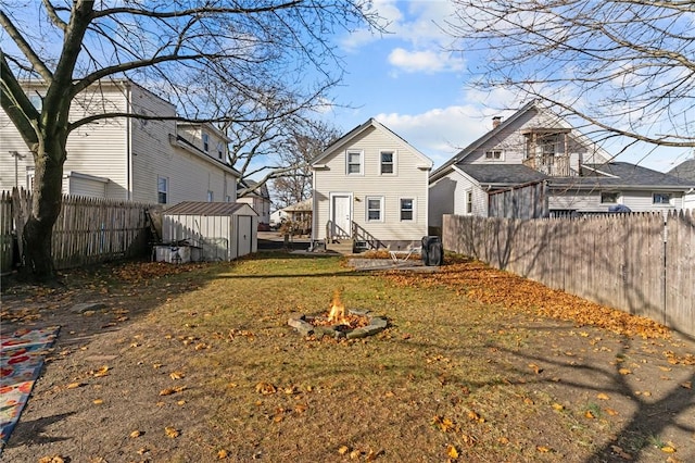 77 Seamans St, Providence, RI 02908 - back of house featuring a fenced backyard, an outdoor structure, entry steps, a storage unit, and a fire pit