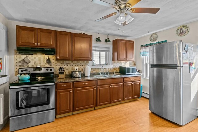 77 Seamans St, Providence, RI 02908 - kitchen featuring a sink, light wood-style floors, under cabinet range hood, brown cabinets, and stainless steel appliances