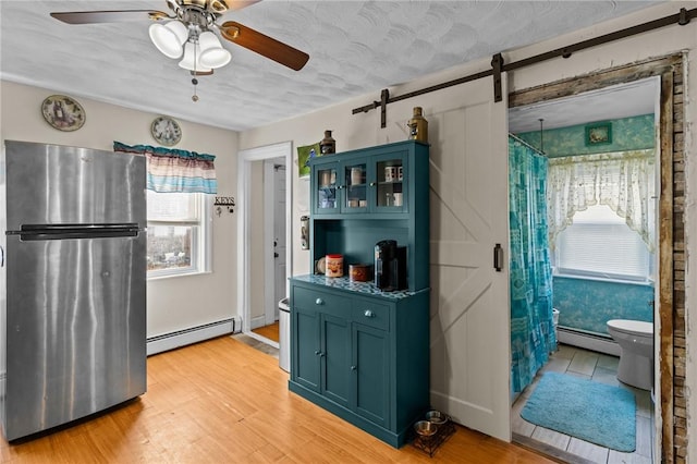 77 Seamans St, Providence, RI 02908 - kitchen with baseboard heating, a healthy amount of sunlight, freestanding refrigerator, and ceiling fan