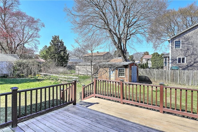 wooden terrace featuring a residential view, a shed, a fenced backyard, an outbuilding, and a yard