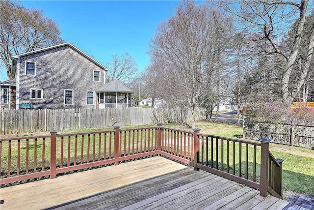 wooden terrace with a sunroom, a fenced backyard, and a lawn