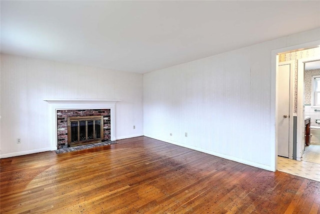 unfurnished living room with a brick fireplace and hardwood / wood-style flooring