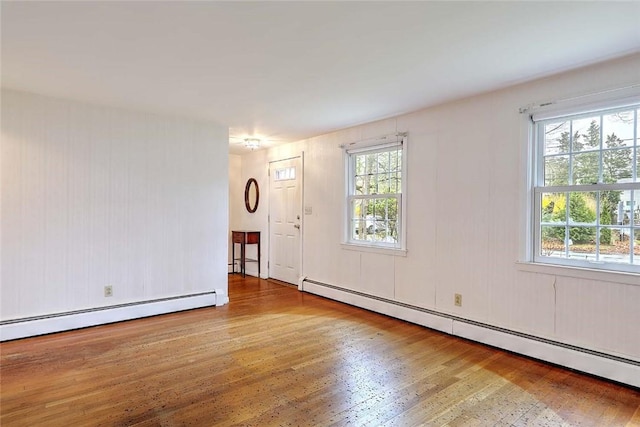 spare room featuring a baseboard heating unit and wood finished floors