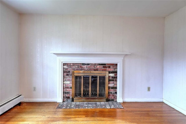 details with wood finished floors, a baseboard heating unit, a fireplace, and baseboards