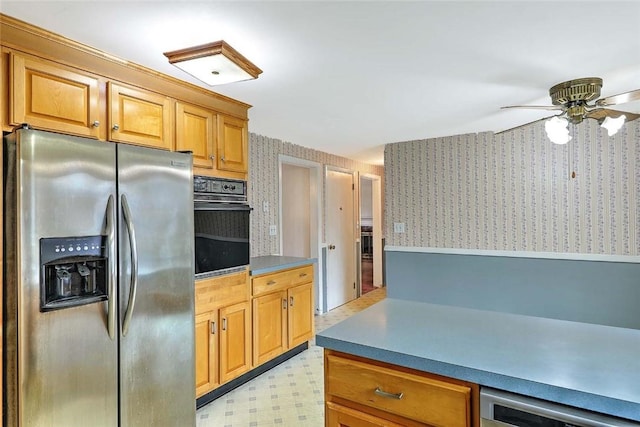 kitchen with wallpapered walls, ceiling fan, stainless steel fridge, and black oven